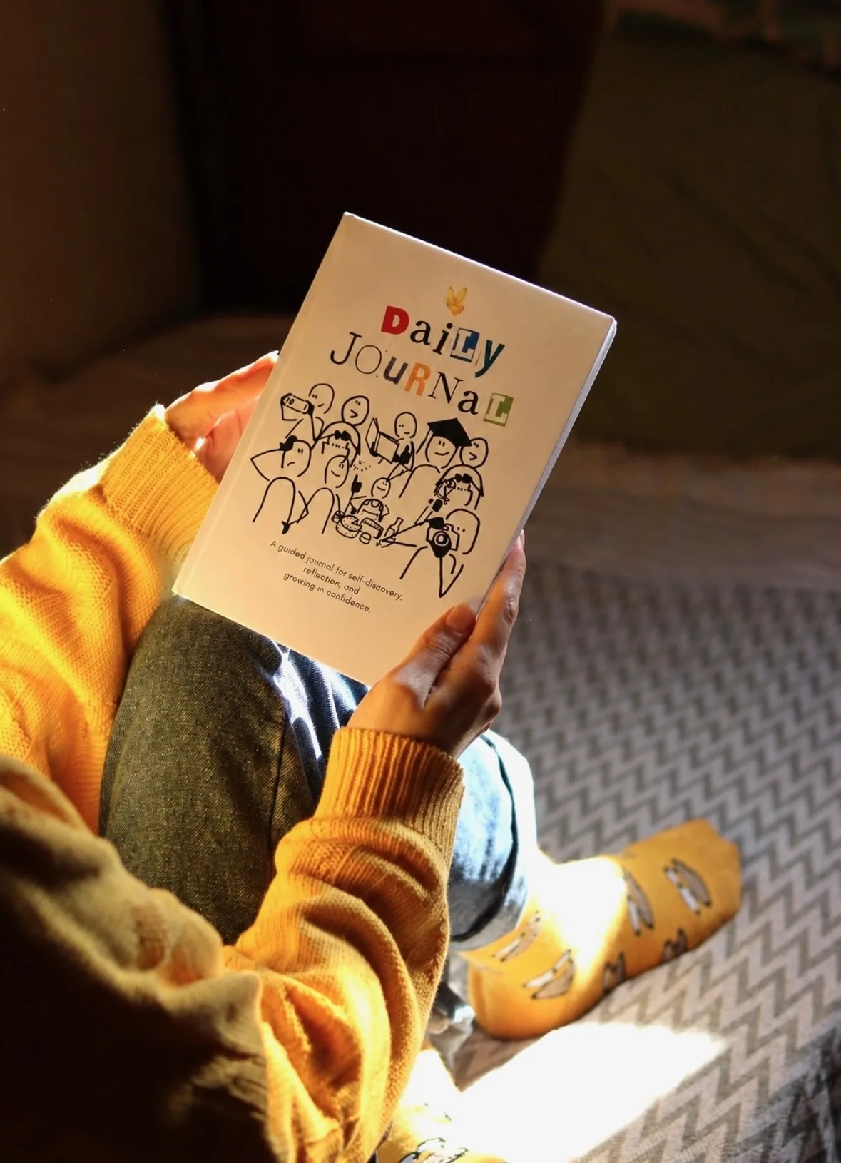 A child holding My First Journal while seated