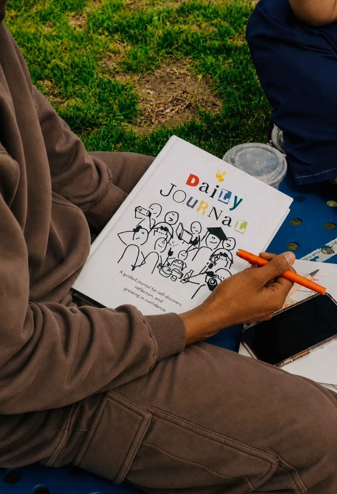 A teenager holding My First Journal with a pen