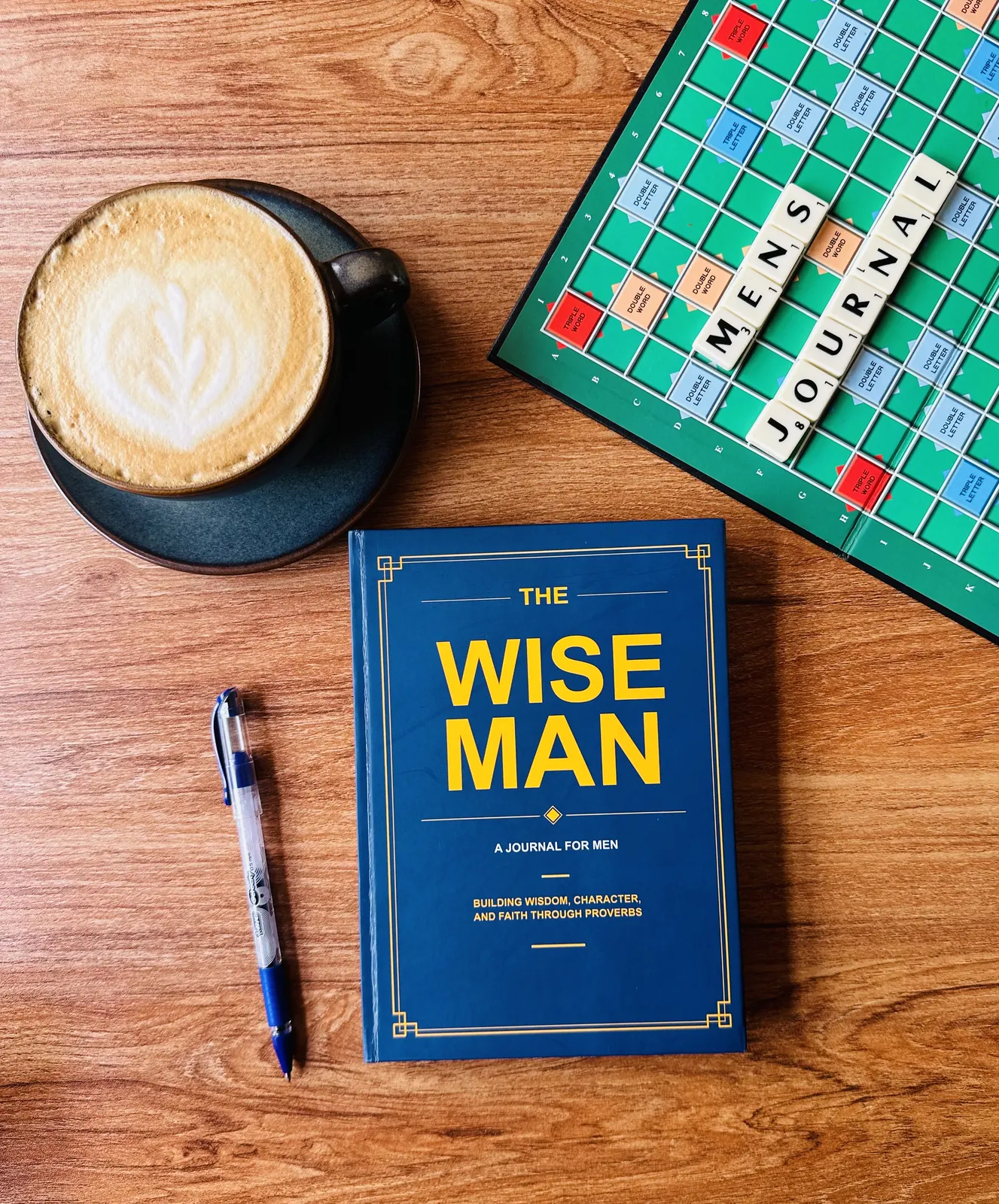 The Wise Man Journal on a desk with coffee, a pen, and a word puzzle